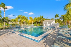 A rectangular swimming pool with a tiled edge, surrounded by lounge chairs and palm trees. - X1114 Schefflera Ct 4 Bedroom Home (Captiva)