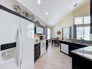 A kitchen with a refrigerator, microwave, stove, and water dispenser. - Luxury 5bd 3.5ba Pool Home In Windsor Palms Resort 5 Bedroom Villa (Kissimmee)