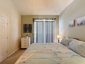 A bedroom with a bed, a dresser, a lamp, a window with curtains, and two wall-mounted pictures. - Luxury 5bd 3.5ba Pool Home In Windsor Palms Resort 5 Bedroom Villa (Kissimmee)