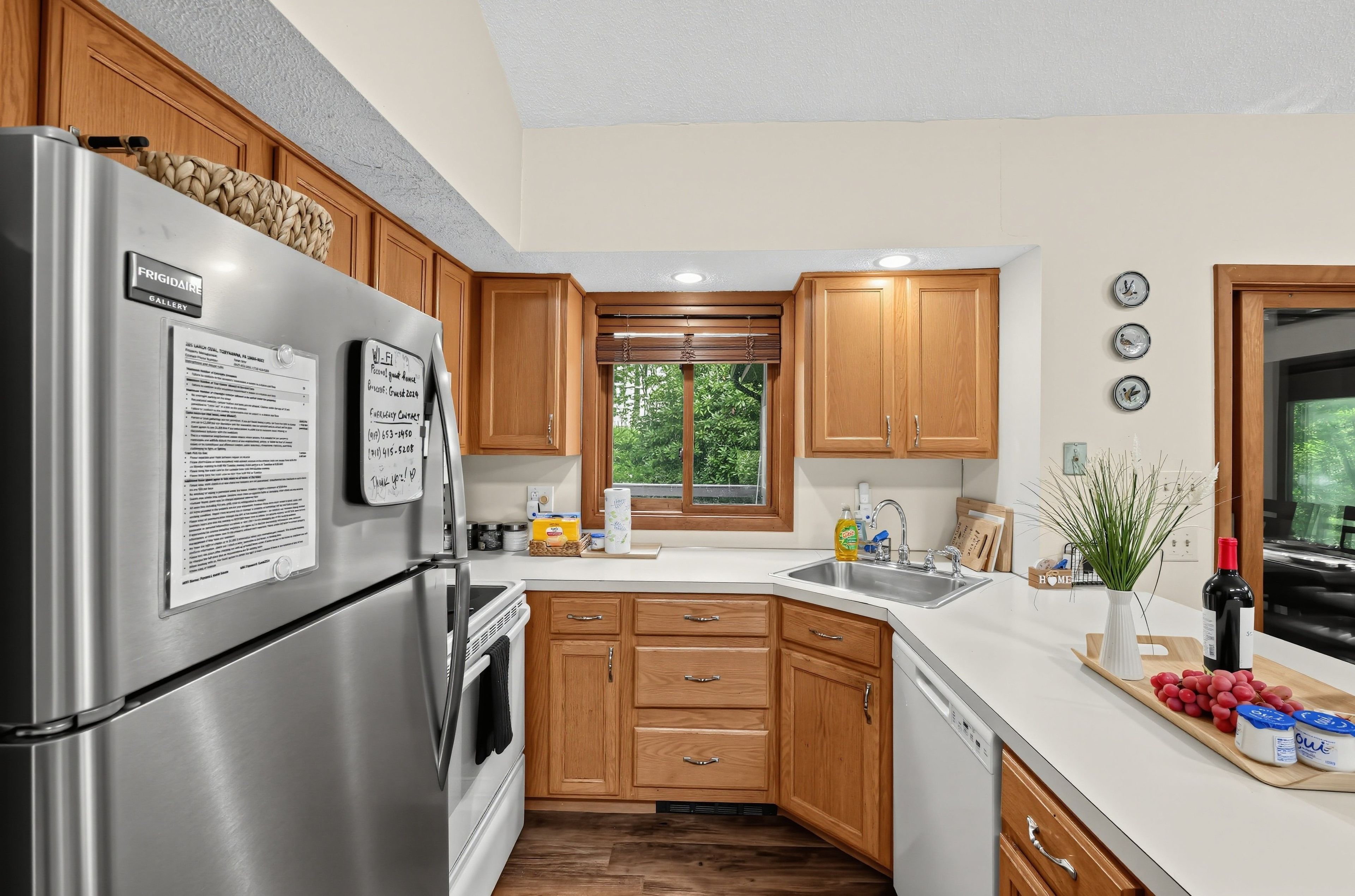 A modern kitchen with stainless steel appliances, wooden cabinets, and a large window providing natural light.