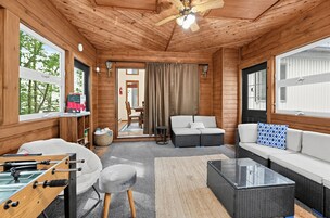 A cozy room with a foosball table, a sofa, a coffee table, and a ceiling fan.