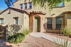 A two-story house with a stone entrance, a covered patio, and a landscaped front yard. - Villa Encore 3 Bedroom Townhouse (Scottsdale)