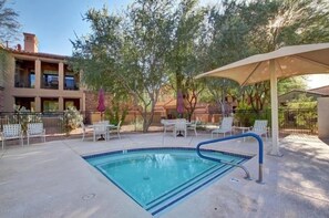 An outdoor swimming pool with lounge chairs and umbrellas, surrounded by trees and a building. - Villa Encore 3 Bedroom Townhouse (Scottsdale)