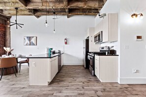 Een moderne keuken met een centraal eiland, witte kasten en een zichtbare brandblusser.