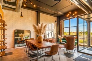 A modern dining area with a wooden table, chairs, and decorative plants. - The Brickline Loft Near NYC + Gym + Parking (Kearny)