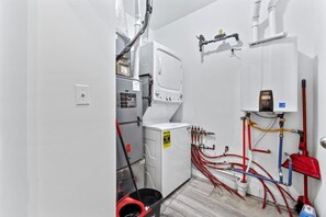 Ein Waschraum mit Waschmaschine, Trockner und verschiedenen Sanitärrohren.