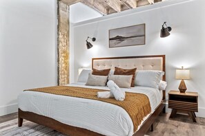 Ein modernes Schlafzimmer mit einem großen Bett, einem Holzkopfstück und einem Nachttisch mit einer Lampe.