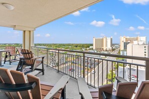 Ein Balkon mit Stühlen und einem Tisch, mit Blick auf einen Parkplatz und Gebäude.