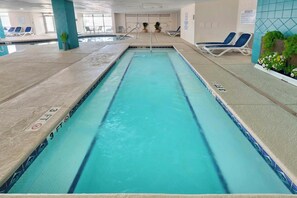 Ein Hallenbad mit klarem Wasser, geteilten Bahnen und Liegestühlen rundum.