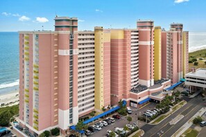 Un hôtel à plusieurs étages, doté de balcons, d’un parking et offrant une vue sur la plage.
