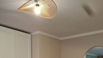A bedroom with a bed, a wardrobe, a mirror, and a hanging light fixture.