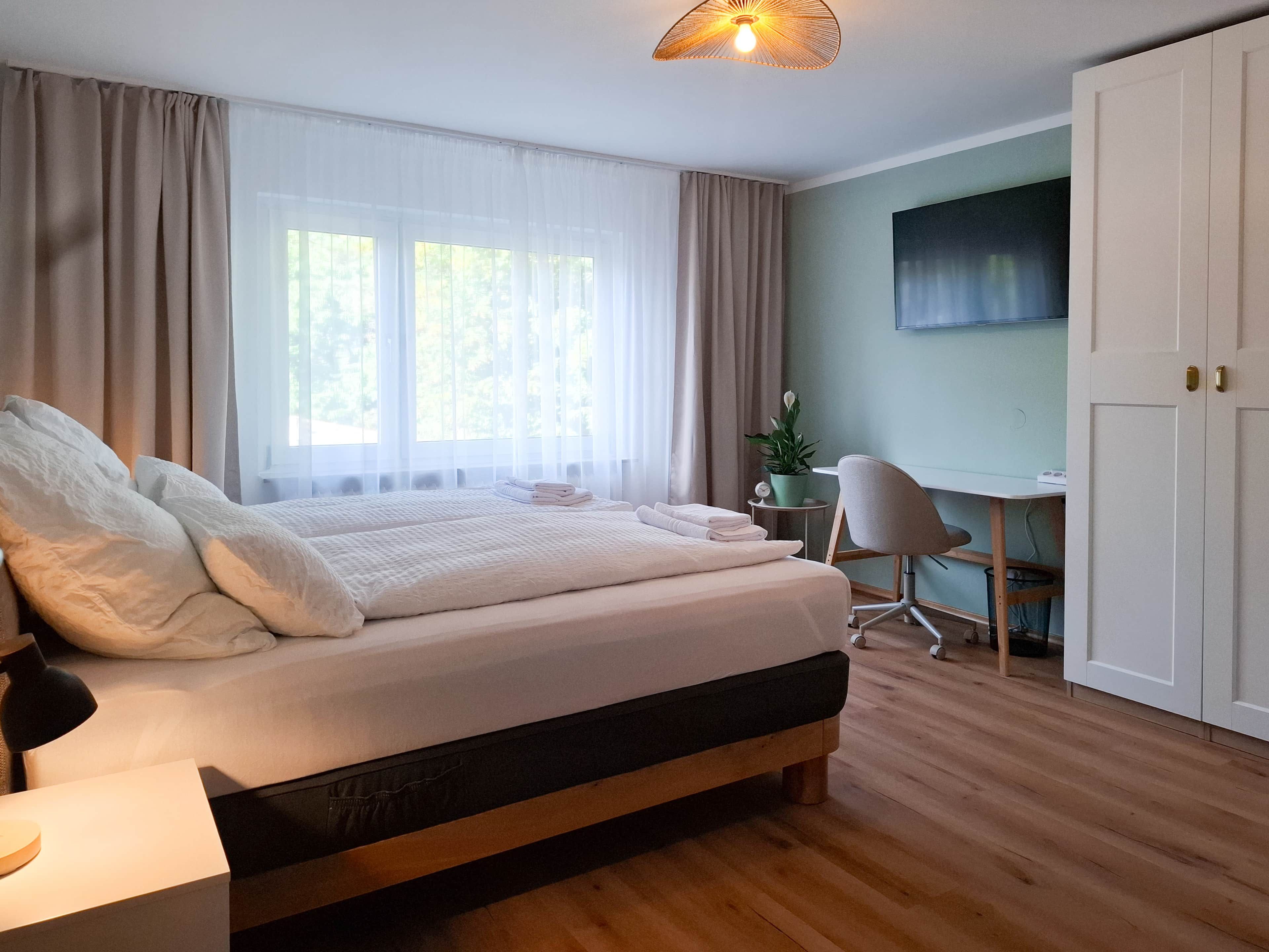 A bedroom with a bed, a desk, a chair, and a wardrobe.