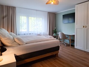 A bedroom with a bed, a desk, a chair, and a wardrobe.