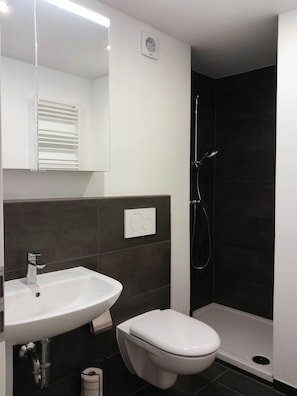 A modern bathroom with a white sink, a toilet, and a shower area. - Nexpo Hub Apartment, 5 minutes from the trade show + parking (Nürnberg)