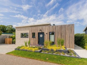A modern two-story house with a brick facade, a wooden front panel, and a black door with the number 46. - Holiday Home in Renesse With Swimming Pool (Renesse)