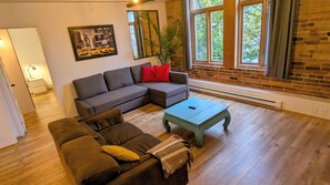 A living room with a sectional sofa, a coffee table, and a potted plant. - Saint-Roch neighbourhood with indoor parking (Québec)