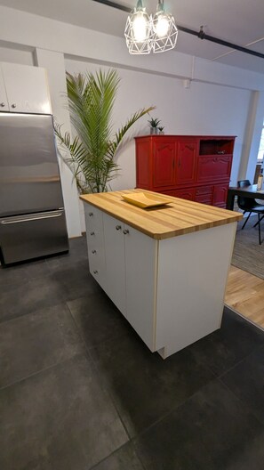 Eine Küche mit einem Edelstahl-Kühlschrank, einer Holz Arbeitsplatte und einem roten Schrank.