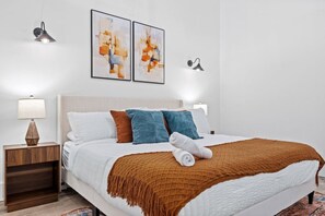 A hotel room with a bed, a nightstand, a lamp, and two wall-mounted light fixtures. - The Garden Loft Near NYC + Parking + Patio (Kearny)