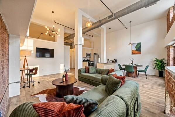 Ein modernes Wohnzimmer mit einer Eckcouch, einem Couchtisch und einem Essbereich mit Stühlen.