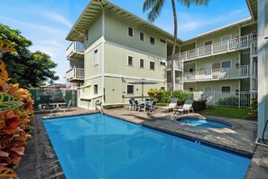 A two-story building with a swimming pool, outdoor seating, and a fenced garden area. - Makolea#21: Steps from the Beach, Beautifully Appointed 2 bedroom condo (KAILUA KONA)