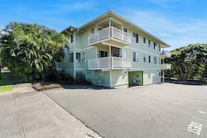A multi-story building with balconies and a green entrance. - Makolea#21: Steps from the Beach, Beautifully Appointed 2 bedroom condo (KAILUA KONA)