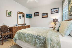 Un dormitorio con cama, cómoda, silla y obras de arte colgadas en la pared.