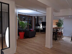 A spacious living area with a large window, a dining table with chairs, and a red potted plant. - Stunning condo with a view, parking, and fireplace (Québec)