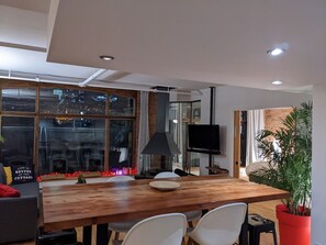 A modern dining area with a wooden table, white chairs, and a large window with city lights visible outside. - Stunning condo with a view, parking, and fireplace (Québec)