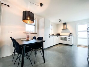 A modern kitchen with white cabinets, a black dining table, and chairs. - Ok20 Holiday Home Oostkapelle (Oostkapelle)