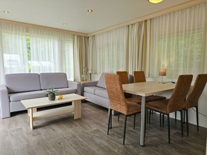 Ein modernes Wohnzimmer mit einer Couch, einem Couchtisch und einem Essbereich mit Stühlen und einem Tisch.