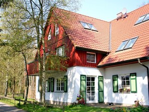 A two-story house with a red roof and white walls, featuring green shutters and a visible satellite dish. - Holiday Apartment With 2 Bedrooms (Ostseebad Prerow)