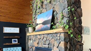 Una chimenea de piedra con un cuadro enmarcado encima, un sofá azul y un techo de madera.