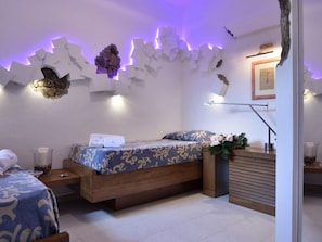 Ein modernes Schlafzimmer mit einem hölzernen Bett, einem Nachttisch, einer Lampe und dekorativer Wandkunst.