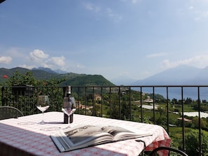 A table with a book and wine glasses, overlooking a mountainous landscape with a view of the sea. - Casa Runsel Bonassi (Tignale)