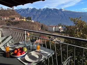 Ein Balkon mit einem Frühstückstisch, mit Blick auf eine gebirgige Landschaft.