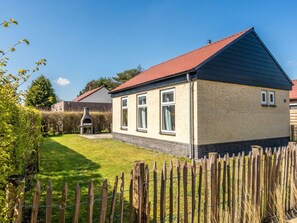 Ein Wohnhaus mit Backsteinfassade, rotem Dach und umzäunter Grundstück.