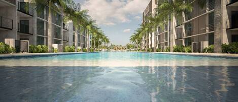 A modern hotel with a central swimming pool, surrounded by palm trees and contemporary buildings.