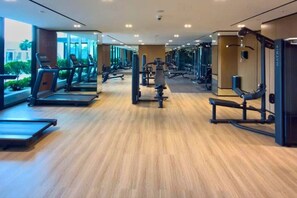 A modern gym with treadmills, weight machines, and a wooden floor. - Studio in JVC near Circle Mall l Pool & Gym (Jumeirah Village Circle)