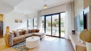A modern living room with a sectional sofa, a round coffee table, and a flat-screen TV. - Family-Friendly 3 Bed Villa l Private Garden (Town Square)