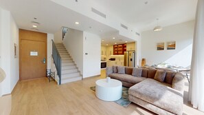 A modern living room with a staircase, a sofa, and a dining area. - Family-Friendly 3 Bed Villa l Private Garden (Town Square)