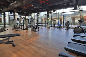 A gym with cardio equipment, weight machines, and a wooden floor.