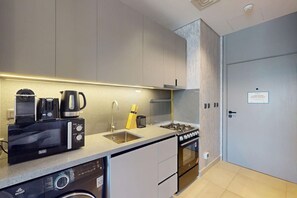 A modern kitchen with a dishwasher, coffee maker, stove, and sink. - Upgraded Studio in Meydan l Peaceful Community (Meydan)