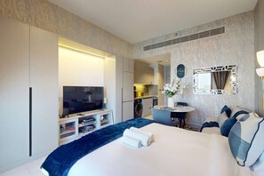 A modern hotel room with a large bed, a television, a small kitchen area, and a bathroom. - Upgraded Studio in Meydan l Peaceful Community (Meydan)