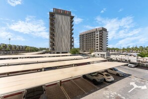A parking area with multiple levels of parking, a covered section, and a view of two high-rise buildings in the background. - Upgraded Studio in Meydan l Peaceful Community (Meydan)