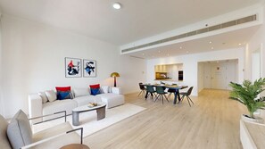 A modern living room with a sofa, coffee table, and dining area. - Spacious 2 Bed with Sea View in The Palm (Palm Jumeirah)