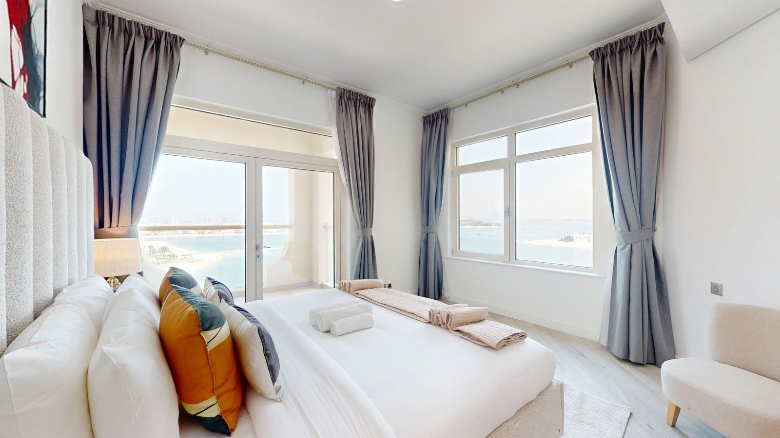 A hotel room with a large bed, a sofa, and a view of the sea.