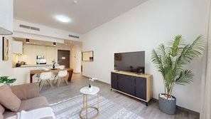 Ein modernes Wohnzimmer mit einer Couch, einem Essbereich, einem Fernseher und einer Topfpflanze.