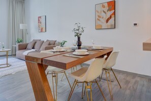 Ein stilvoller Essbereich mit einem Holztisch, gedeckt für vier Personen, umgeben von weißen Stühlen mit goldenen Beinen.