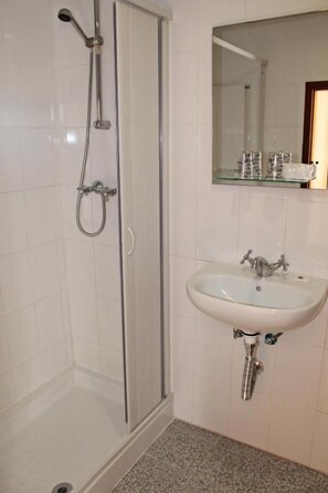 Une salle de bain avec une douche, un lavabo et un miroir.