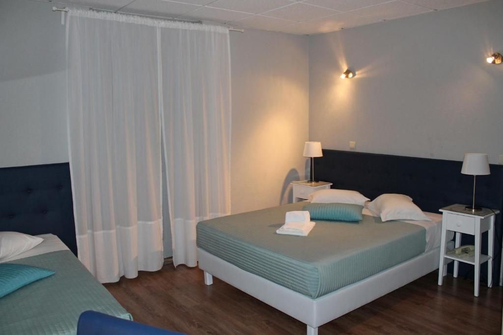 Una habitación de hotel con una cama individual, dos mesitas de noche, una lámpara y una cortina.